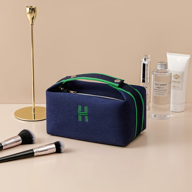 Stylish eprolo portable premium canvas makeup bag in navy blue with green accents, shown beside cosmetic products and makeup brushes, ideal for traveling and organizing beauty essentials.