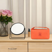 Orange canvas makeup bag by eprolo, displayed alongside a mirror and cosmetics, emphasizing its fashionable design and practical storage capability.