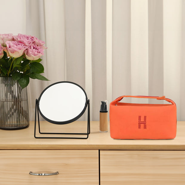Orange canvas makeup bag by eprolo, displayed alongside a mirror and cosmetics, emphasizing its fashionable design and practical storage capability.